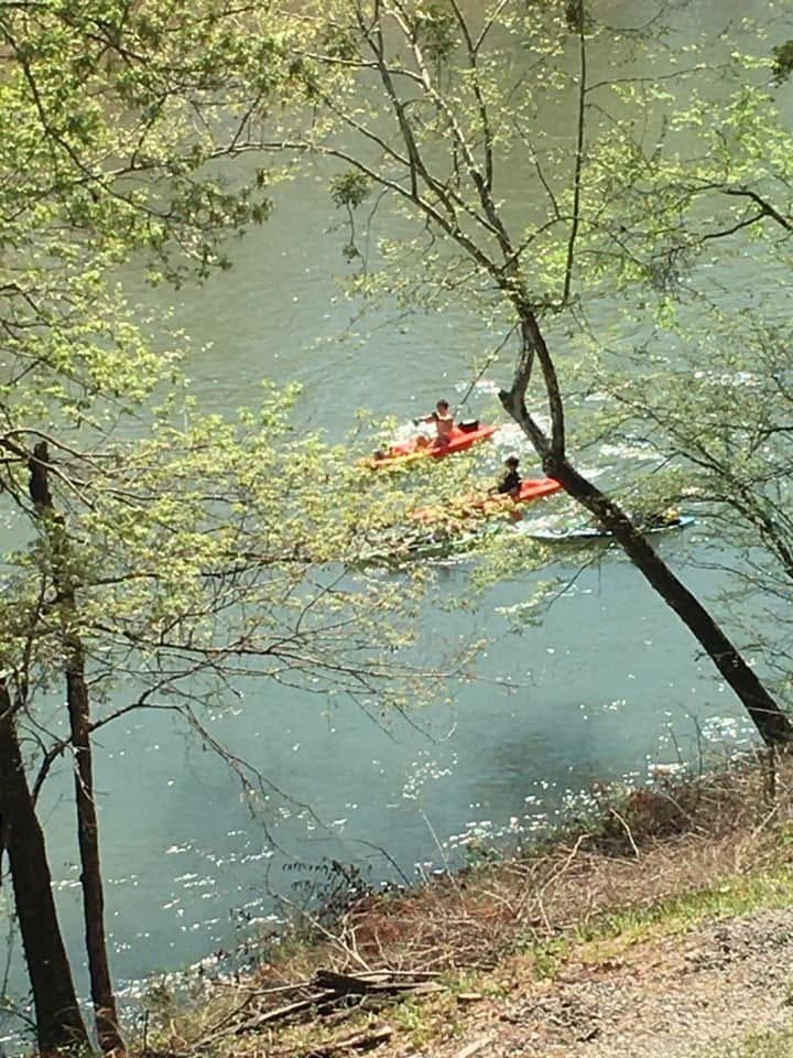 Kayakers passing below a wooded hillside on the Caddo River